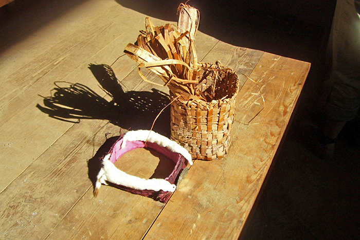 Woven cedar basket and indigenous head dress sitting on table.
