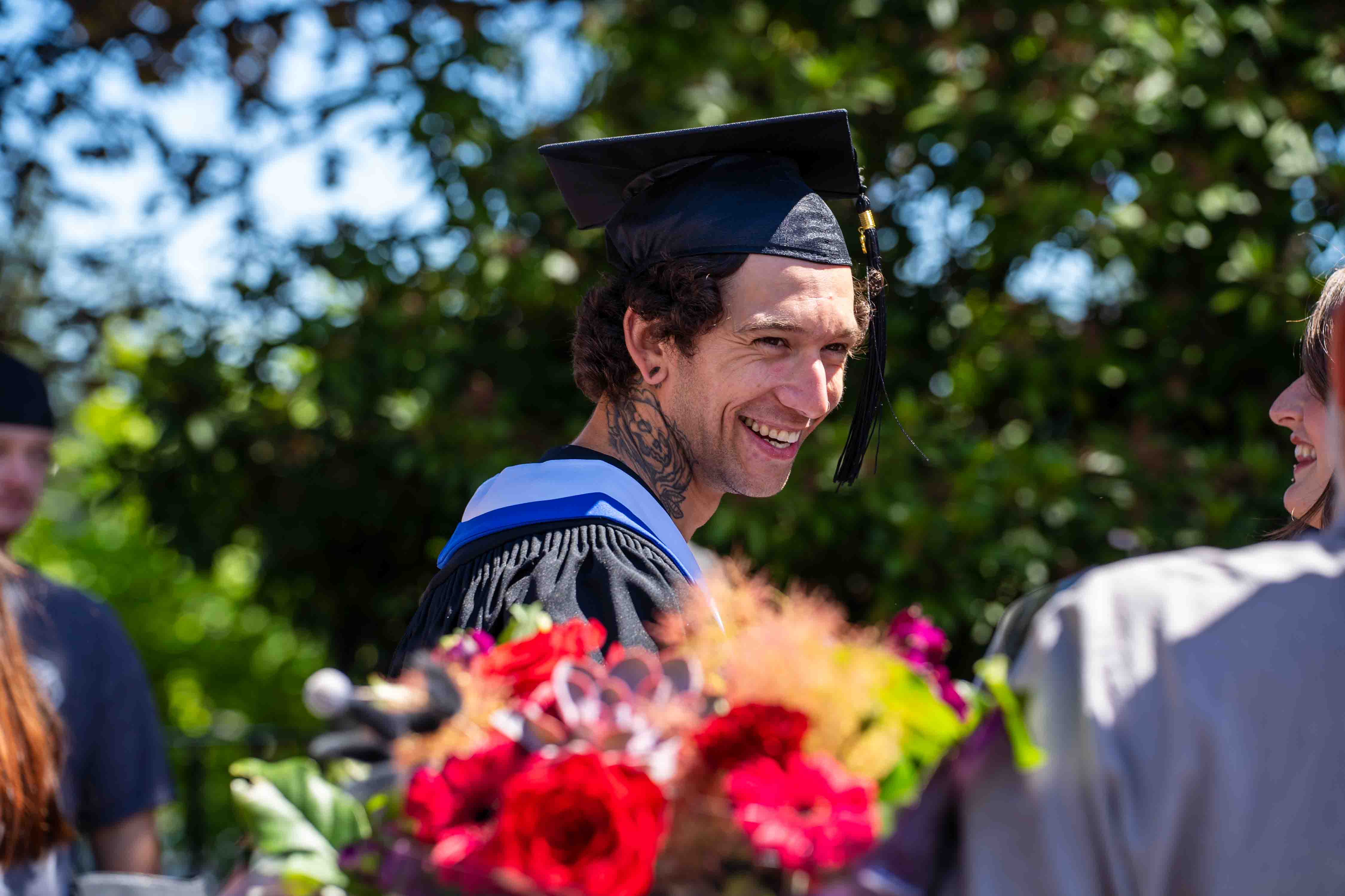 A graduate celebrates with family in the courtyard after the 2026 convocation ceremony