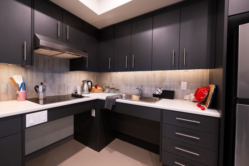 NIC student housing family suite, showing accessibility features in the kitchen area, including low light switches, accessible area under stovetop and kitchen sink.