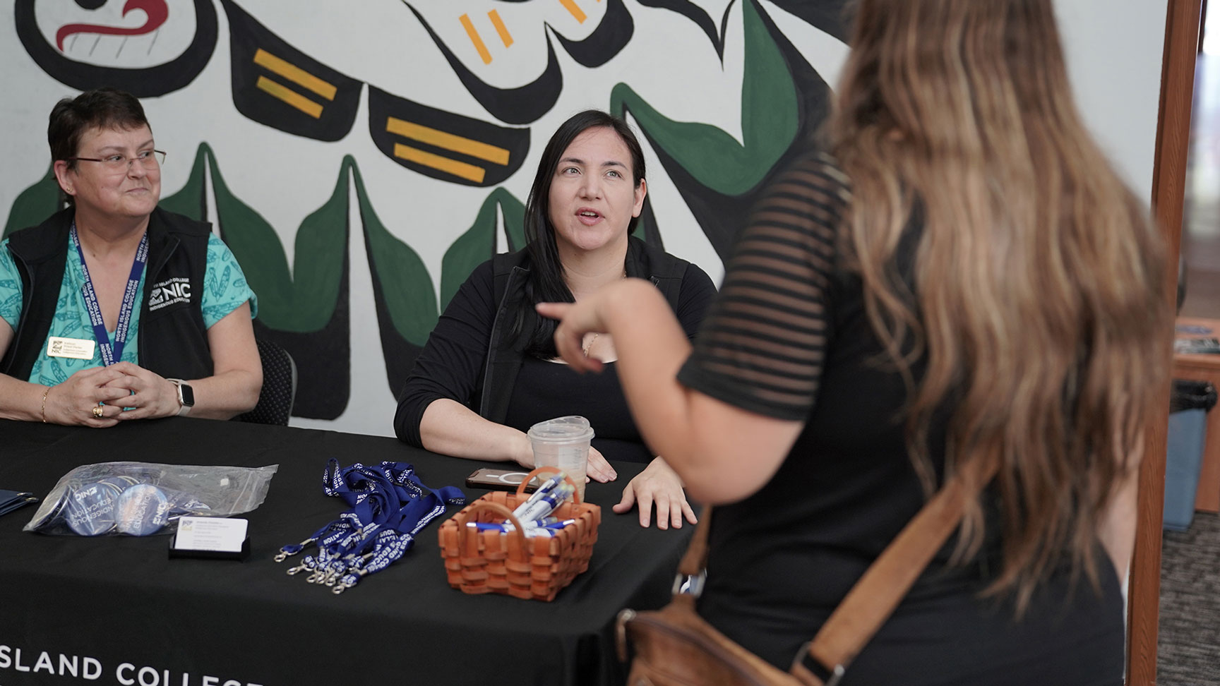 Two college representative answer questions at orientation event
