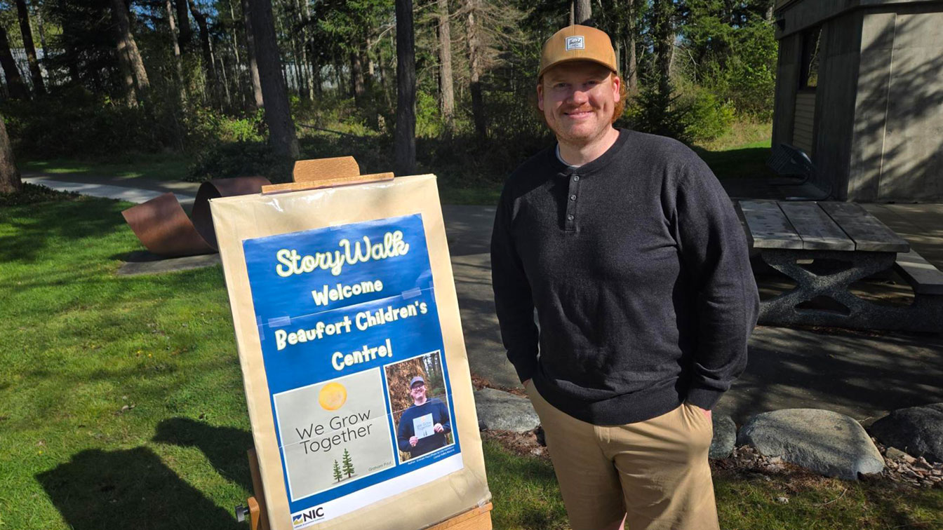 A writer poses near a poster for an event based on his book