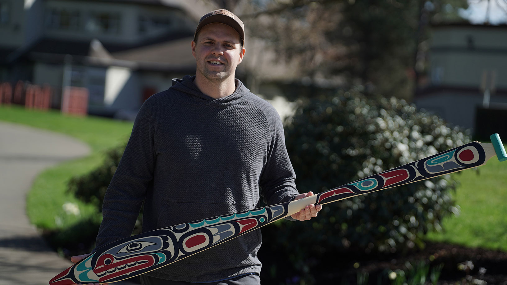 A First Nation artists holds a ceremonial paddle.