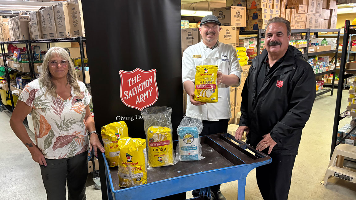 A culinary instructor holds a bag of flour donated by the Salvation Army for a food security program