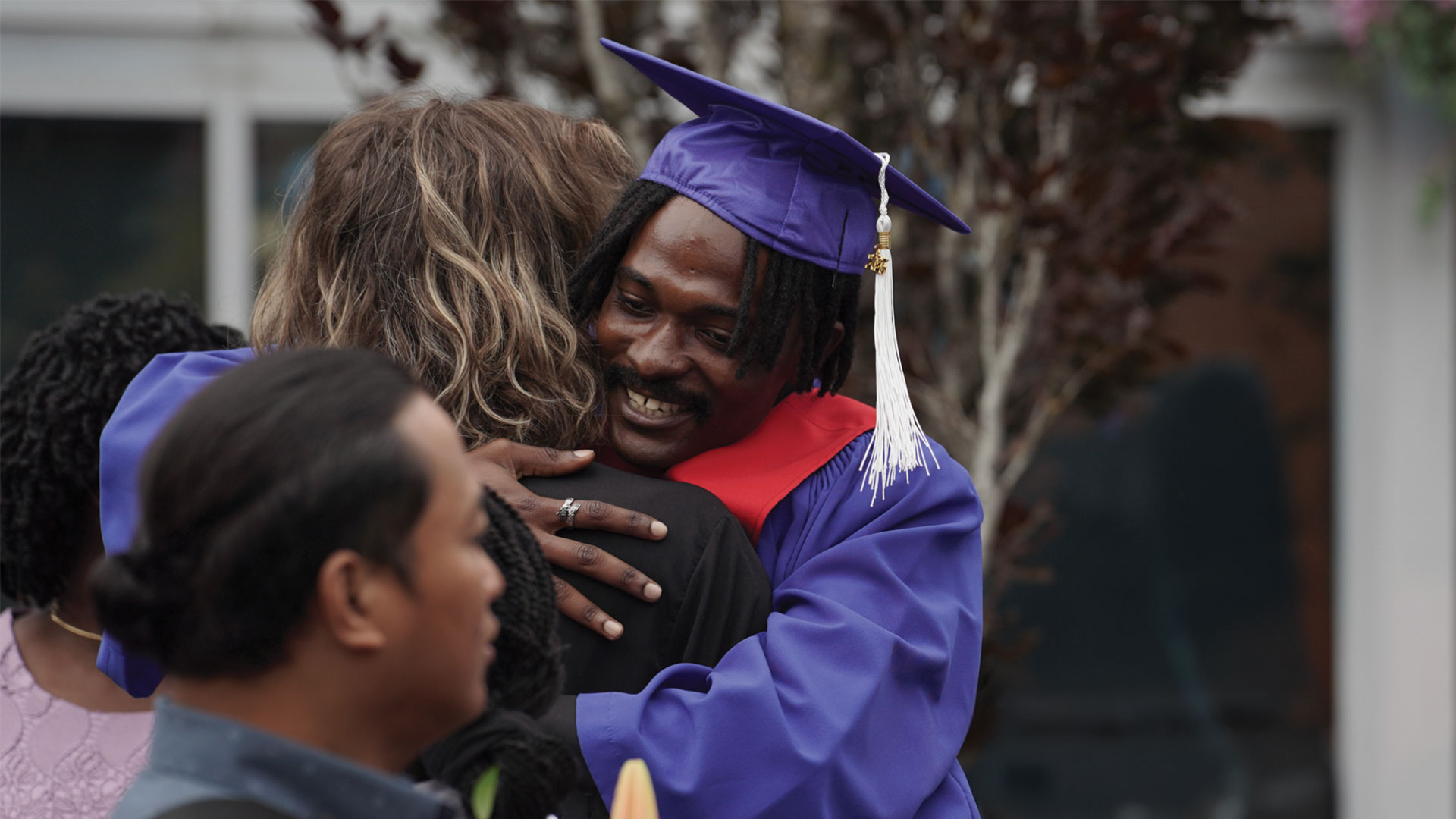 student hugging supporter at convocation ceremony outdoor reception