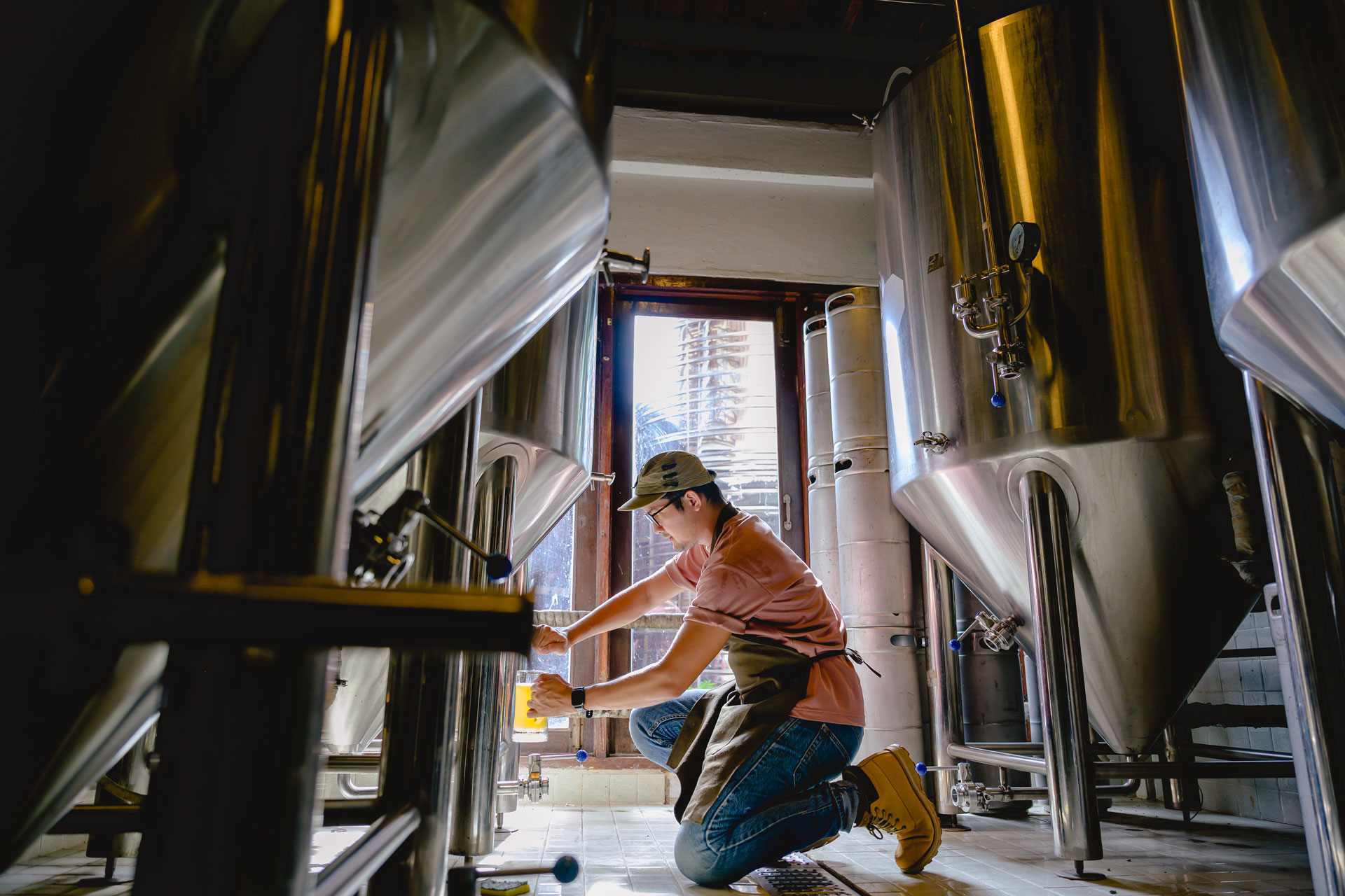 Craft Brewery employee testing beer from a fermenter
