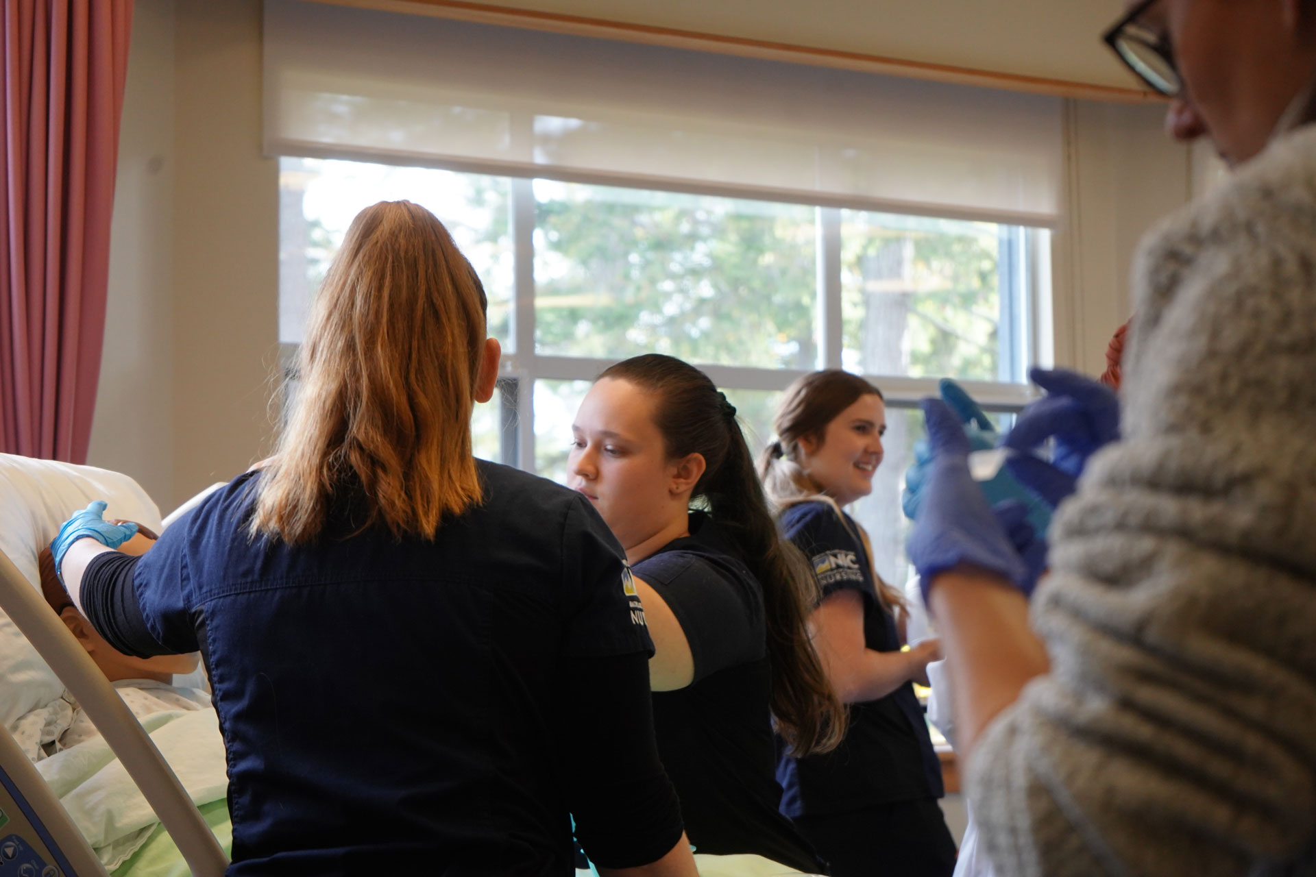 Nursing students in the Comox Valley campus nursing lab learn on a mannequin in a hospital bed