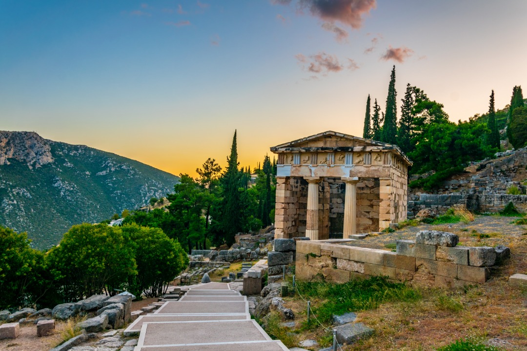 Architectural structure with columns at Delphi Greece. The photo is taken at sunrise. Mountains in the distance.