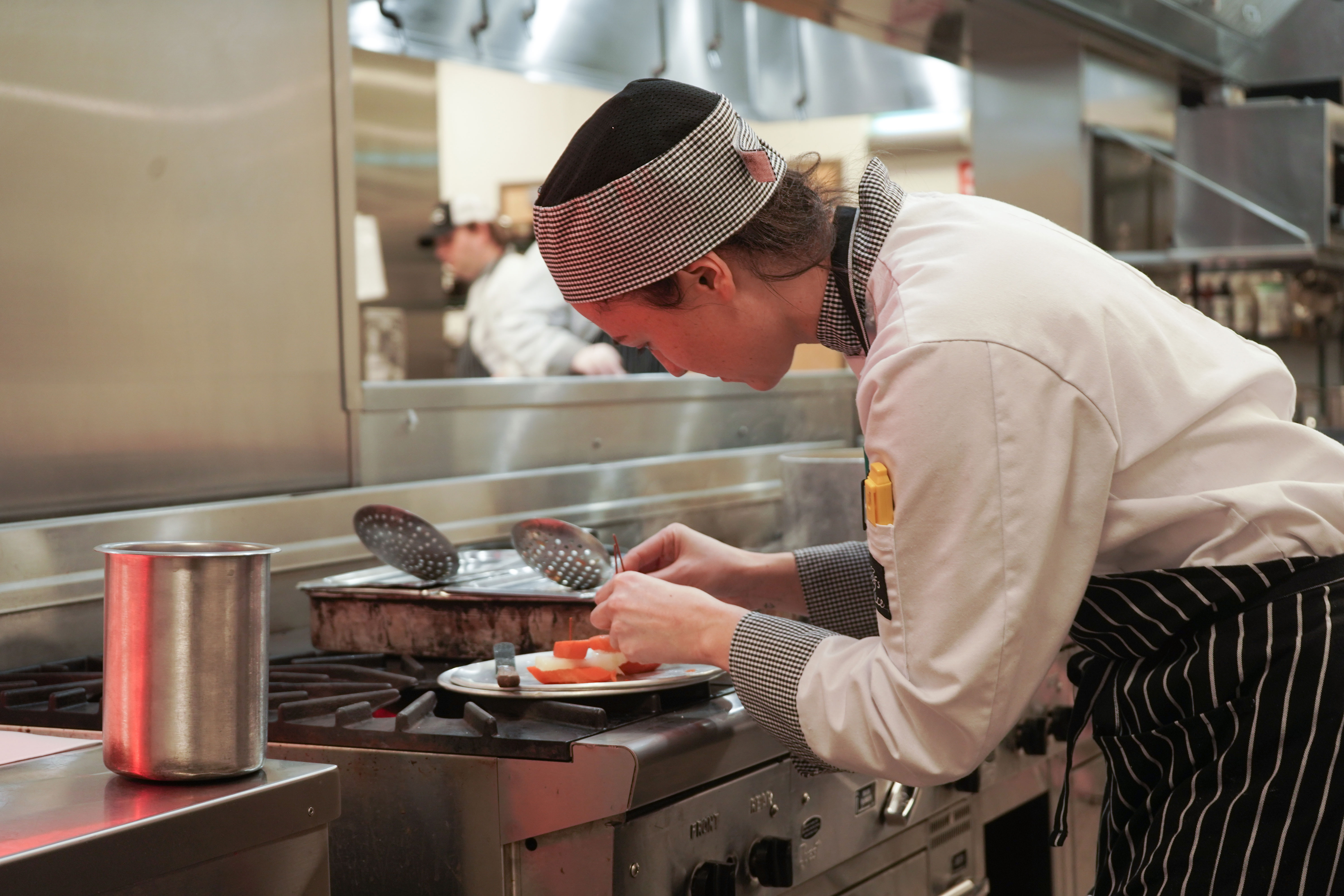 Culinary student at NIC's Campbell River culinary kitchen plates vegetables.