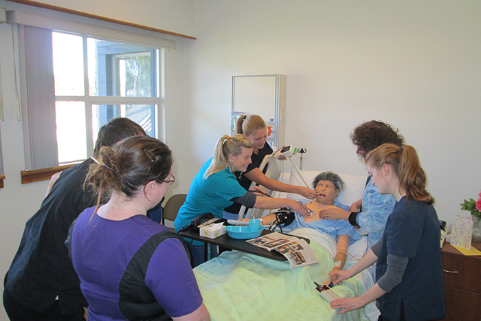 Students in the nursing lab do a hands-on assessment on a simulated patient