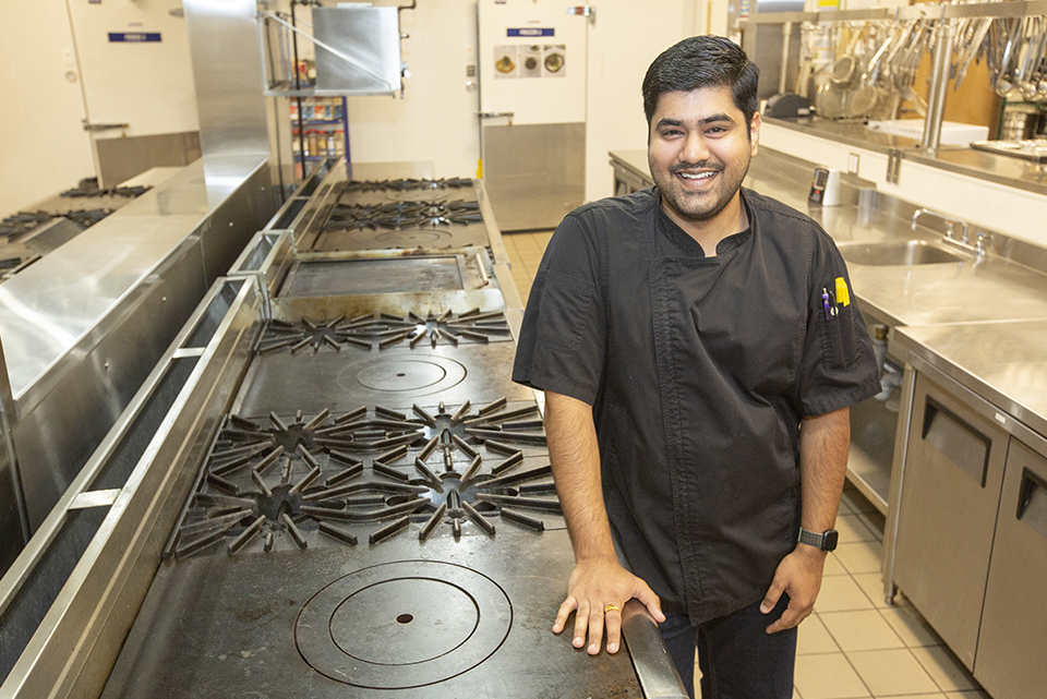 Kartik Goel Culinary Business Operations Diploma Alum stands in kitchen