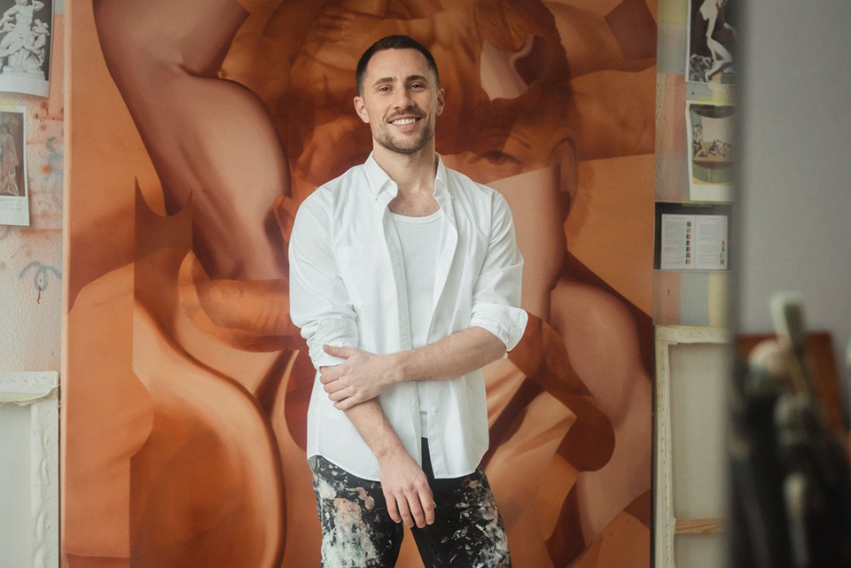 Artist Andrew Moncrief stands in front of painting
